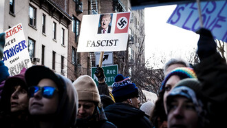 A shallow focus photo of a person holding a Donald Trump sign during an immigrant rights protest in the West Village, New York City, USA