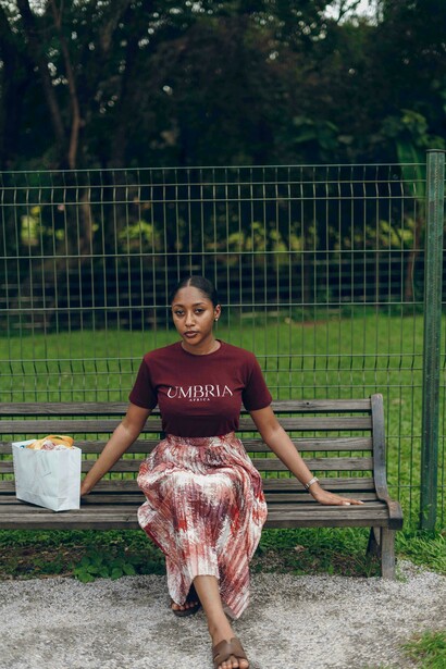 A young woman seated on a park bench, lost in thought