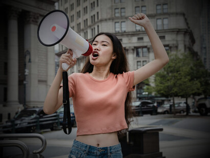 A young protester with a megaphone outside government buildings, echoing how youth challenge institutions to listen and respond