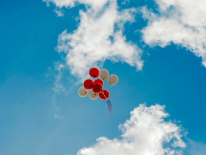 A cluster of balloons flying high against a clear, open sky