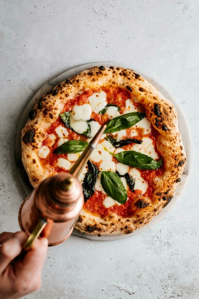 Olive oil drizzled like a blessing over the sacred crust of pizza