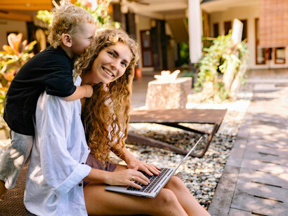 A mother juggling work while engaging with her child, presenting the invisible labour that keeps economies running