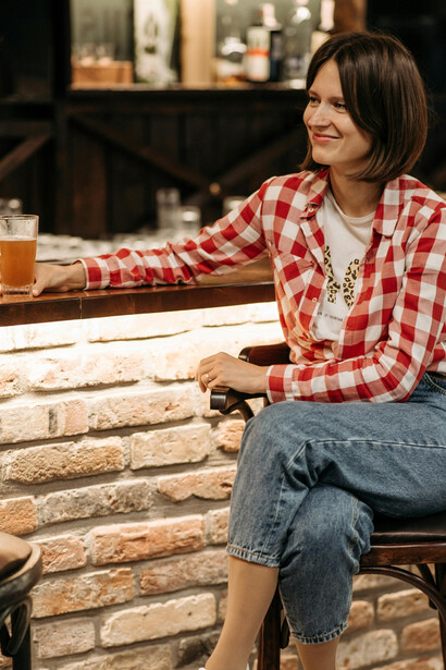 A woman relaxes with a beer at a pub table, enjoying her own company
