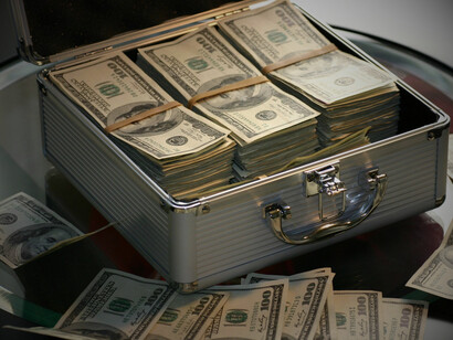A pile of money in a suitcase, representing how the industry profits not only through expensive medical bills, but also through corruption