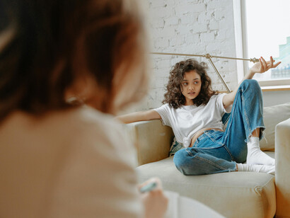 The image of an upset female teenager listening to her therapist symbolizes Gen Z’s battle with anxiety, depression, and emotional burnout