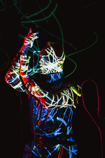 A man standing in a dimly lit room, string lights glowing around him as lightning flashes within his body