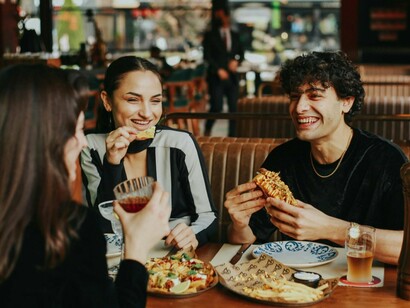 Three friends engaged in a cheerful conversation over food, reflecting the power of shared moments and storytelling