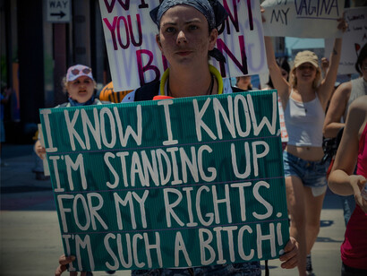 A woman holding a placard that advocates the need for gender equality, signifying the ongoing fight for gender equality in society