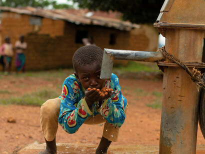 A child drinking water from a tap in his village, highlighting the need for access to clean and safe drinking water and other such facilities in rural areas