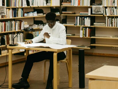 Jovem concentrado em sua pesquisa. O tempo passou rápido: já eram quase duas horas de pesquisas. Havia levado seu tablet e fazia várias anotações no bloco de notas do aparelho – até alguns hieróglifos se arriscara a copiar. Estava tão concentrado que não percebeu a aproximação de um recém-chegado, que comentou: "Parece que alguém decidiu mergulhar fundo na Egiptologia hoje!"