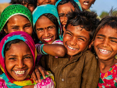 A group of joyful Indian children from diverse ethnic backgrounds in a desert village, India, reflecting the rich cultural diversity explored in the Indian Genome Project