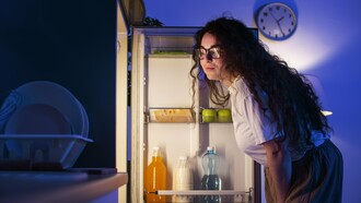 A woman studying her fridge, symbolizing the need to look deeper than dates and cool air