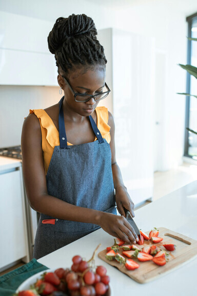 A woman arranging fresh strawberry slices on a wooden plate