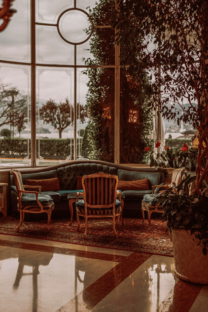 The space features elegant architecture, beautiful views, refined chairs, shimmering chandeliers, classic décor, and luxurious hotel interior design