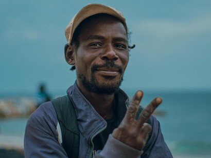 Homem em praia de Luanda, na Angola. Meu amigo sentado na arquibancada e um dos mestres angolanos, Lopes Trigo, riu ao me ver caminhando em direção aos vendedores de gelado - kandengues também. E disse: - Lá vai o general e sua tropa