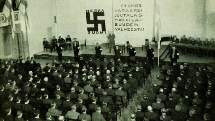 Reunião do partido nazista finlandês SKJ, 1933. Na parede, lê-se: "Libertem o trabalhador da mentira do judaico-marxismo"