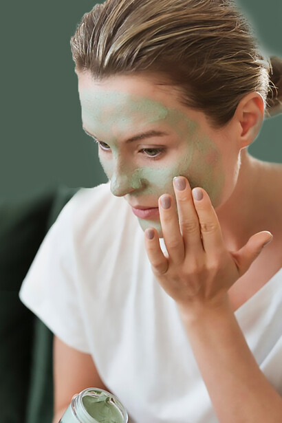 Applying an organic facial mask, the woman focuses on skincare aimed at acne treatment and glowing skin