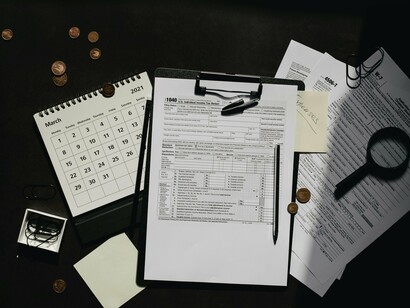 A detailed tax form on a clipboard flanked by budget tools, echoing the need for transparency and traceability in public infrastructure spending