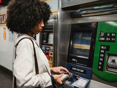 A woman stands at an automated teller machine while completing a cash withdrawal