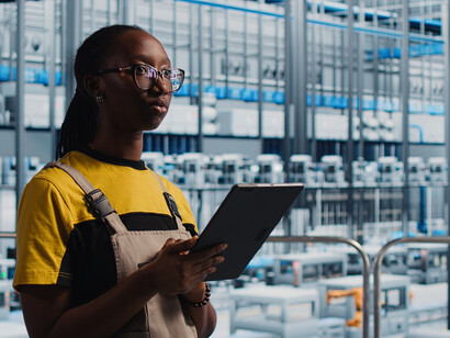 A smart factory engineer uses a tablet to manage AI-driven automated workflows, supporting the factory’s digital transformation