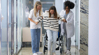 Female doctors assist a patient in a wheelchair with care and professionalism