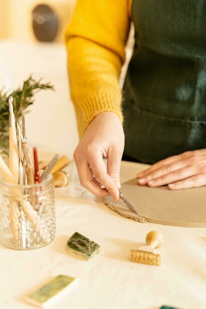 A person in an apron molds clay dough on a worktable as part of an art activity