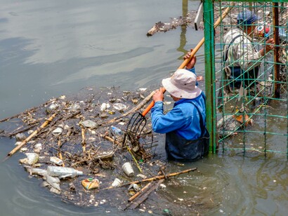 Men work to clear debris from a heavily flooded city street, a stark reminder of how the climate crisis fuels more frequent and destructive floods