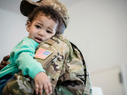 A soldier carries his child while leaving with his family