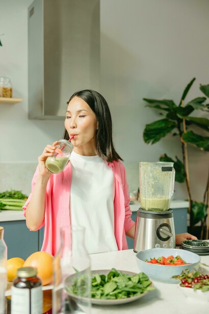 A balanced diet illustrated by a woman drinking a smoothie next to a colorful plate of fruits and vegetables