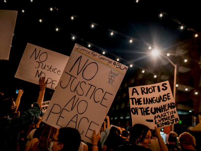 A crowd of demonstrators gathers in a solidarity march against racism, demanding justice, democracy, and social change