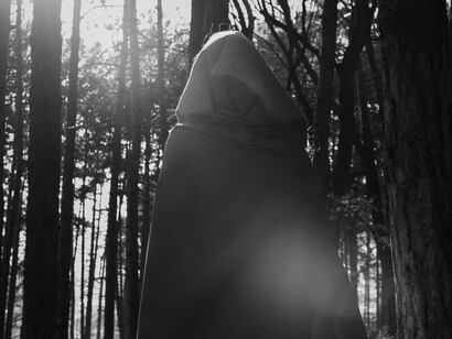 Wrapped in shadow and light, the figure suggests the quiet, relentless watchfulness surrounding ancient power