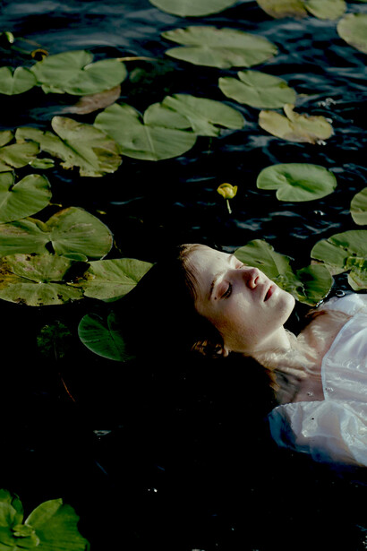 A woman gently floating on calm water surrounded by blooming water lotuses