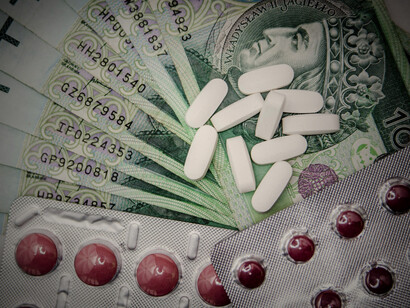 Several pills lying on top of currency notes, symbolising the high cost of healthcare and the financial burden of medical expenses