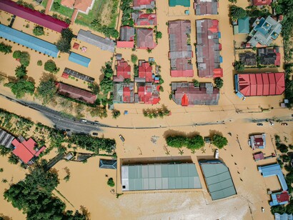 A flooded settlement where only rooftops remain visible, showing the consequences of corruption on disaster-prone regions