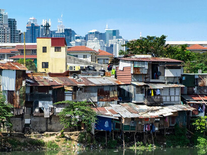 A contrast of poverty and wealth: riverside slums set against the backdrop of towering city buildings