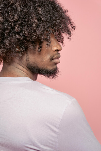 Black man with natural Afro curls partly covering his eyes, serious expression