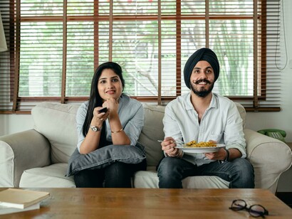 Happy ethnic couple relaxing on the couch while watching an Indian Punjabi movie