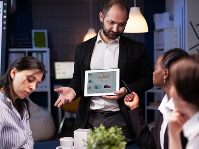 A leader presenting data to colleagues during a meeting, representing the exchange of ideas that depends on attentive listening