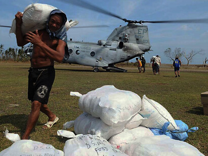 Philippine citizens, government volunteers, and armed forces personnel unload rice, water, and supplies from a U.S. CH-46 Sea Knight helicopter as part of a joint relief effort responding to Super Typhoon Megi
