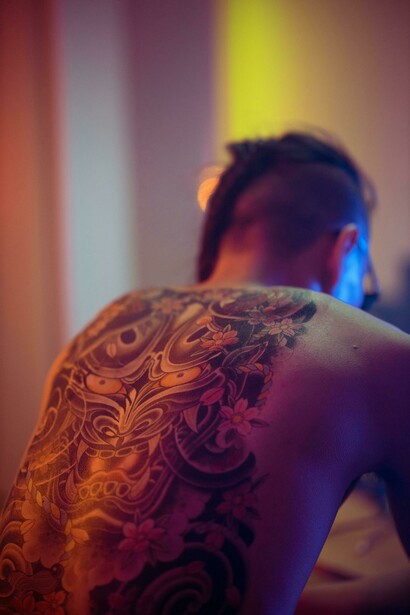 A tattooed Japanese man photographed with a house in the backgroun