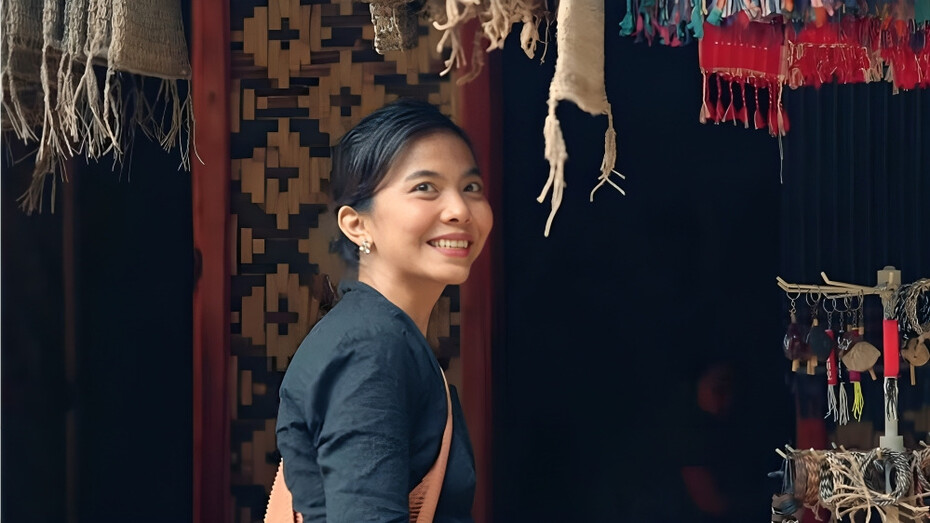 A woman standing in a fabric store, mirroring the Baduy’s devotion to handwoven textiles as carriers of ancestral meaning