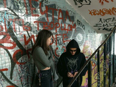 A man and a woman conducting a drug deal in a graffiti-filled abandoned building