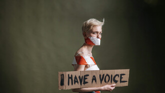 A woman holds a placard that reads “I have a voice”