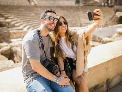 A tourist couple sitting together and taking a selfie with their phone