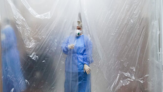 A doctor wearing a mask and lab coat stands behind a tarpaulin during the COVID-19 pandemic in Chernivtsi, Ukraine