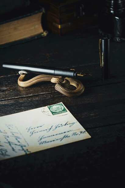A nostalgic flat lay featuring an envelope, a bronze snake trinket, and a handwritten love letter on aged paper