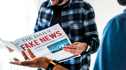 Men reading a newspaper labeled "Fake News," highlighting the impact of misinformation and social media