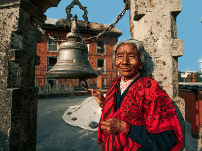 Smiling elder near a historic temple bell in Bhaktapur, Nepal