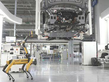 A Boston Dynamics robot navigates a car factory floor, demonstrating the integration of advanced robotics into modern automotive manufacturing