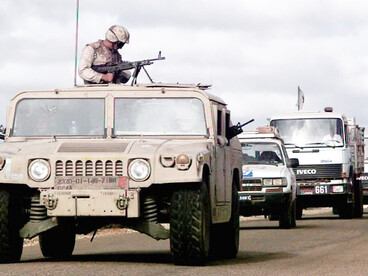 A convoy moves along the road from Mogadishu to Baidoa, led by a desert-camouflaged M998 HMMWV from the U.S. Marines’ 2nd Platoon, “C” Company, 3rd Light Assault Infantry Battalion. A Marine mans an M60 machine gun from the turret as United Nations trucks carrying food supplies for Somali feeding centers follow behind in support of Operation Restore Hope